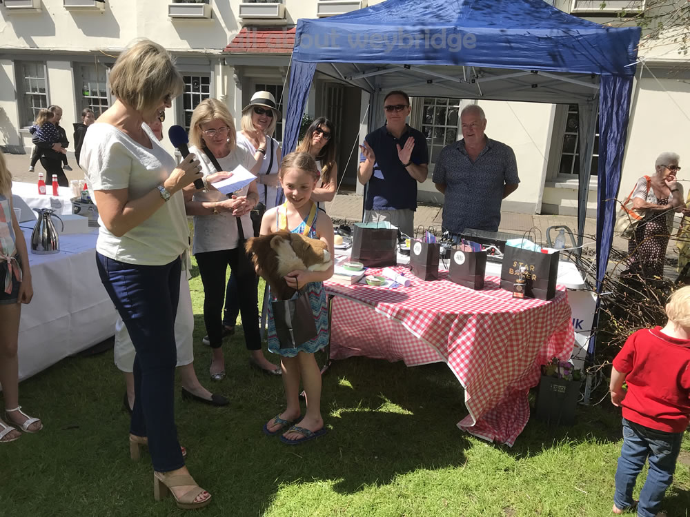 Ruth Langsford presents prizes to a young cake baker with Brooklands Radio presenters Alan Bosson and Barry Richards in the background - at the Great Weybridge Bake Off on Monument Green