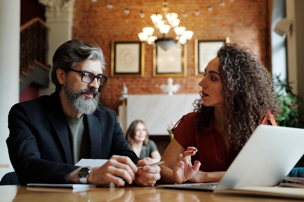 Man in Black Suit Sitting Beside the Woman in Brown Shirt