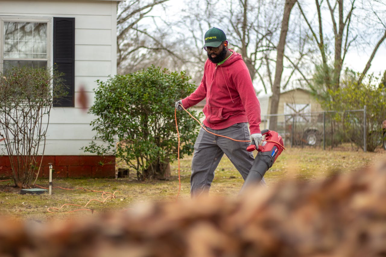 Man in Red Jacket Using a Leaf Blower