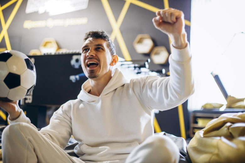 Man celebrating while holding soccer ball indoors