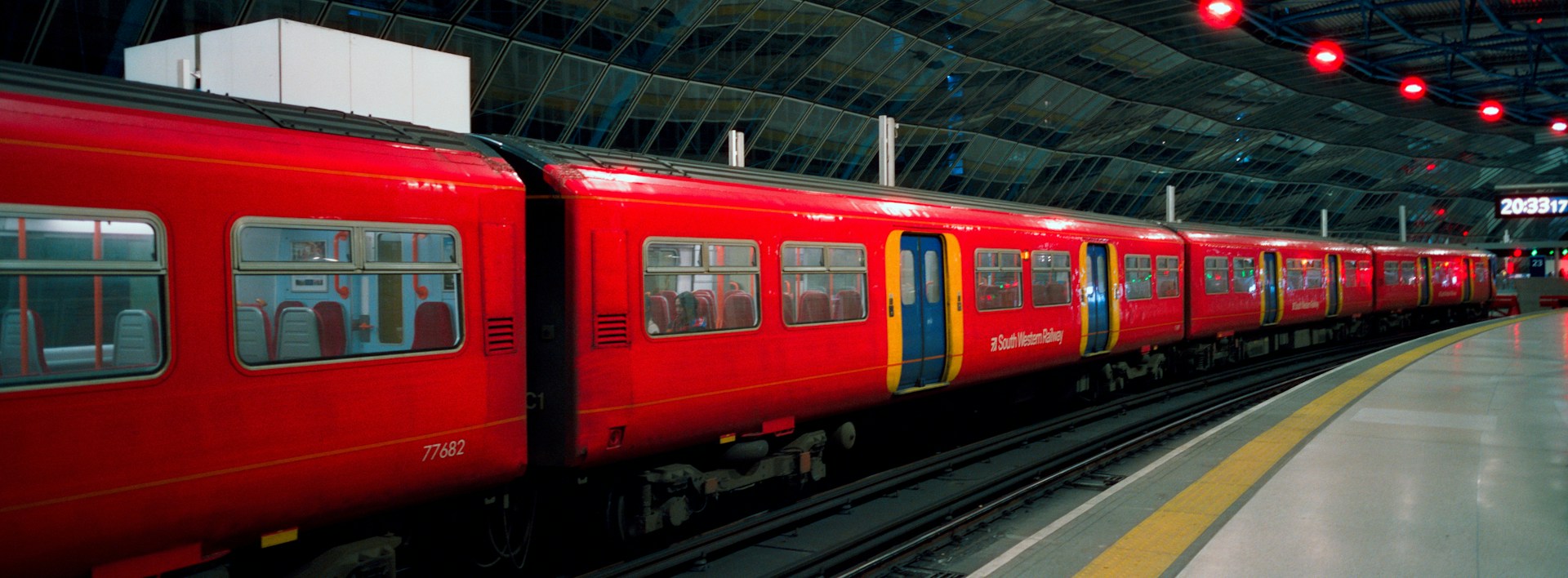 A red commuter train waiting at a London station platform at night, representing the daily commute into the capital<br />
